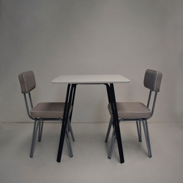 Conjunto de mesa cuadrada blanca y dos sillas de caño gris con tapizado vintage sobre un fondo neutro.