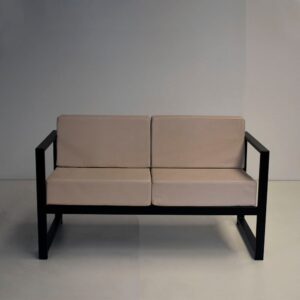Sillón minimalista de dos cuerpos modelo Lena, con estructura de caño negro y almohadones de cuerina color beige.